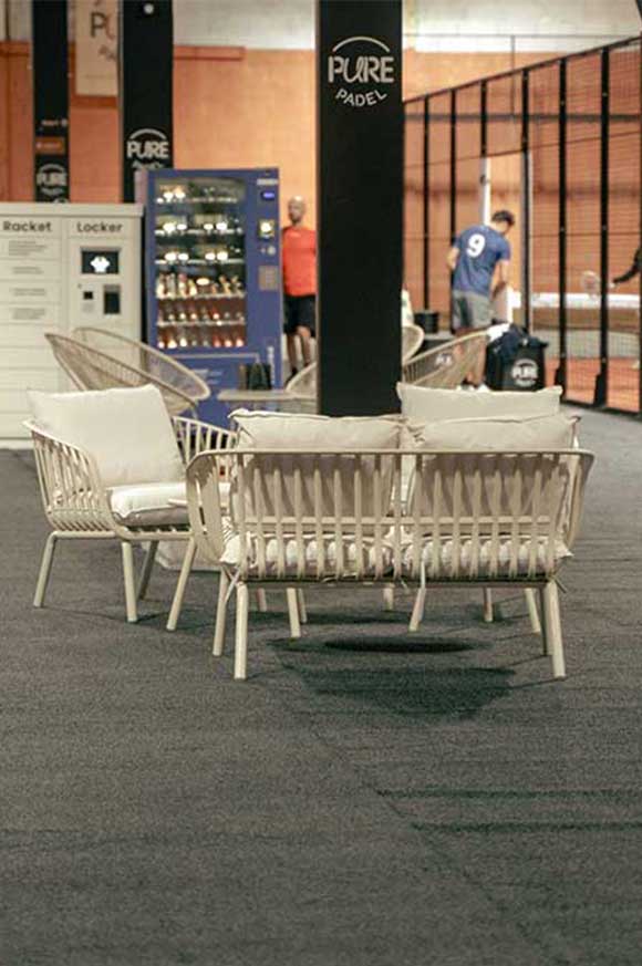 Espace détente entre les pistes de padel avec fauteuils, racket locker et distributeur de boissons. Pure Padel La Roche sur Yon
