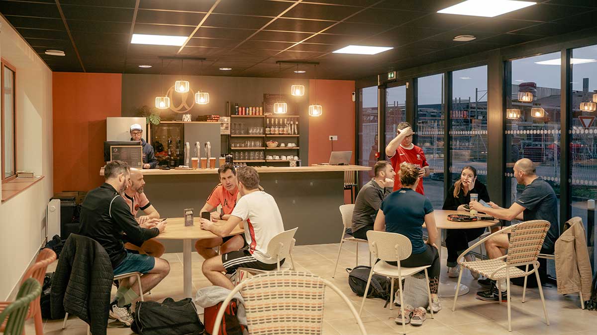 Club house de Pure Padel à Montaigu avec personnes autour des tables et vue sur le bar